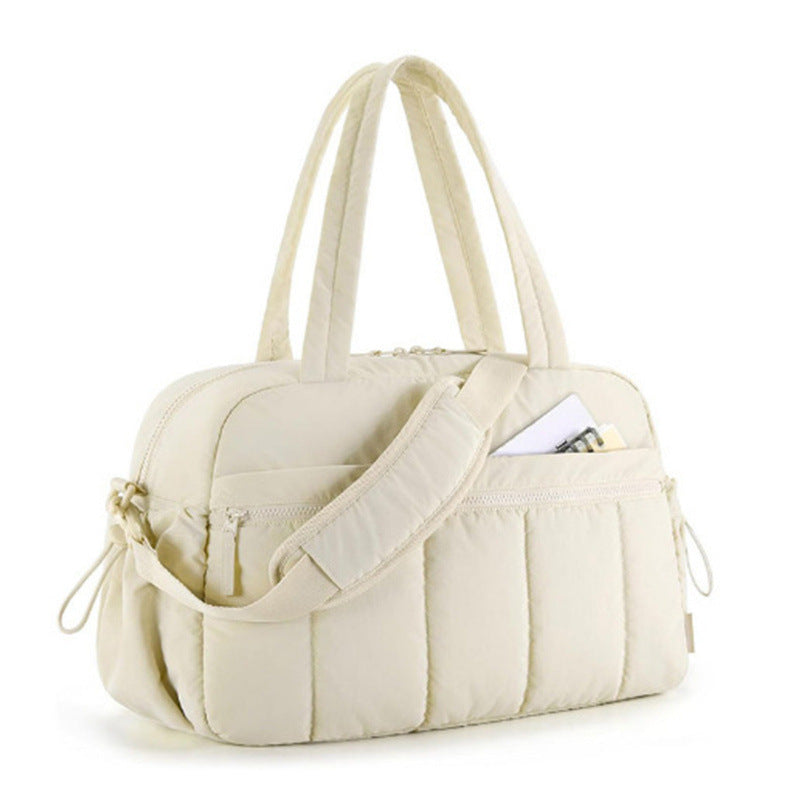 Sac de voyage femme matelassé couleur crème, avec anses confortables, bandoulière réglable et poches zippées, idéal pour week-end et déplacements.