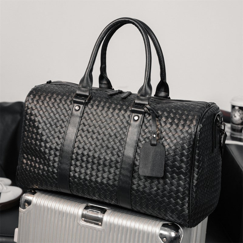 Sac à dos voyageur noir effet cuir haute gamme, sac de voyage posé sur une valise cabine argentée, ambiance aéroport chic et moderne, style business élégant et raffiné.