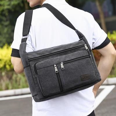 Sac en bandoulière homme noir porté dans le dos sur épaule, plusieurs poches zippées, rangement organisé, style urbain moderne, utilisation quotidienne