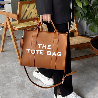 sac week end femme couleur marron porté à la main en intérieur ambiance urbaine chic avec mobilier