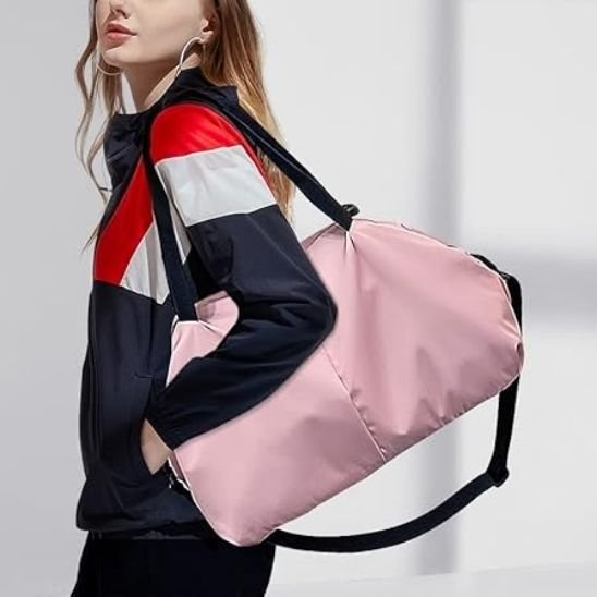 Sac week end femme rose élégant porté à l’épaule par une étudiante marchant près d’un mur vitré