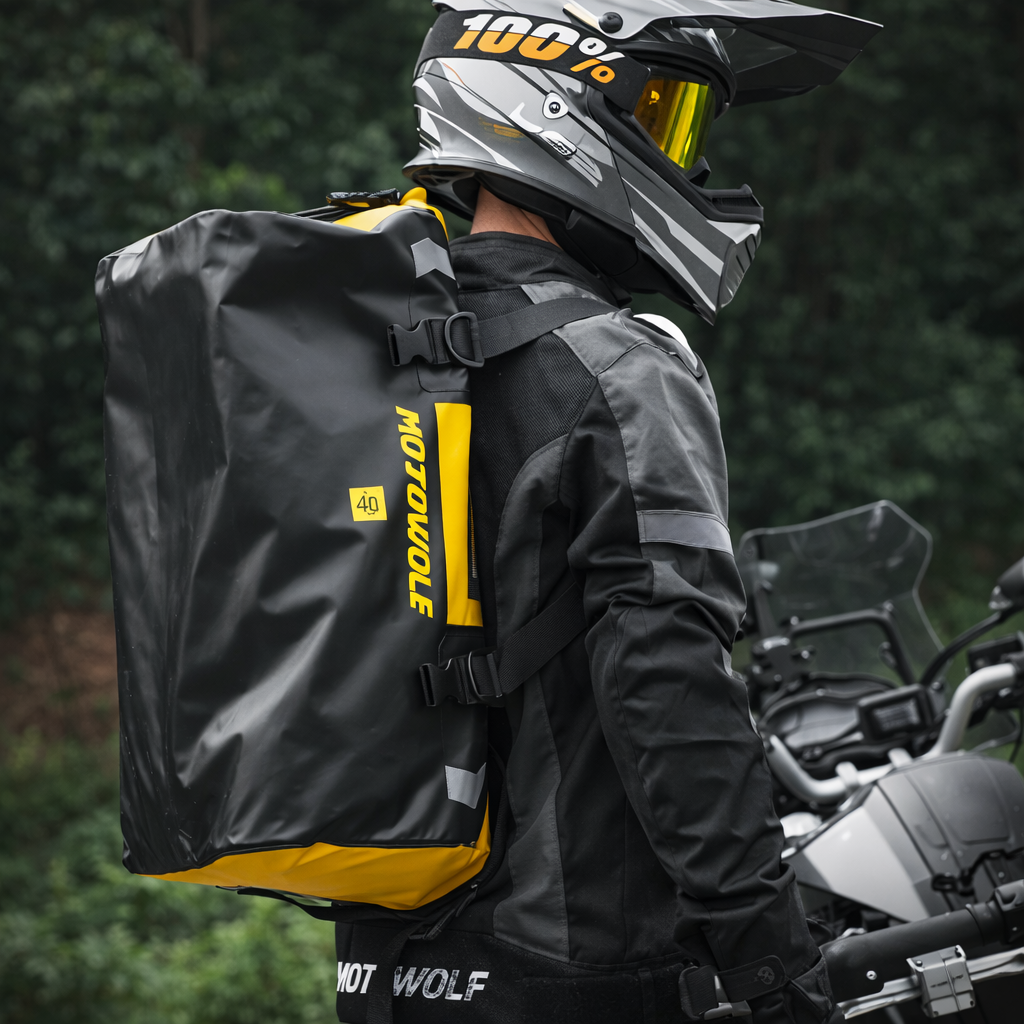 Sac week-end homme jaune porté en sac à dos par un motard équipé, forêt verdoyante autour. Ambiance aventure plein air, visibilité élevée et style fonctionnel.