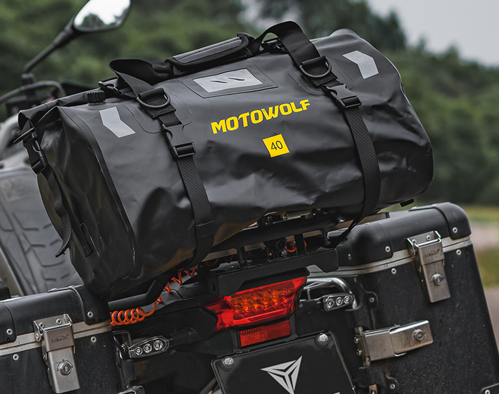 Sac week-end homme noir en gros plan montrant la texture imperméable et les coutures solides présenté sur la partie arrière d'une moto.