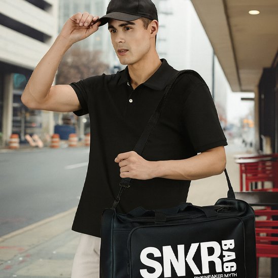 Sac Weekend Zen Noir avec écriture blanche en matière solide porté par un homme habillé en noir qui marche dans la rue