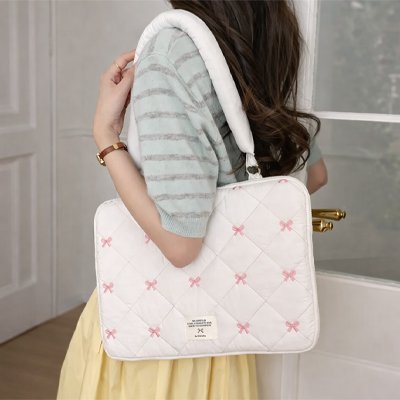 Sacoche ordinateur femme blanche à motifs roses portée à l’épaule, design doux et rembourré pour transporter un ordinateur en sécurité.