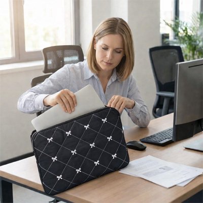 Sacoche ordinateur femme bleu marine matelassée, femme au bureau insérant son PC portable dans une housse élégante et sécurisée.
