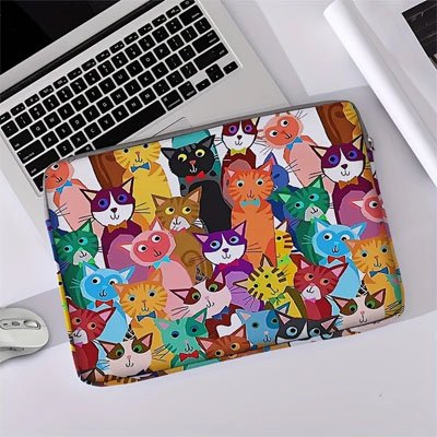 Sacoche pour ordinateur sans poignée à motifs de chats posée à plat sur un bureau blanc, à côté d’un ordinateur portable et d’une souris.