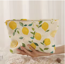 trousse a maquillage à citrons tenue à la main sur nappe en dentelle,