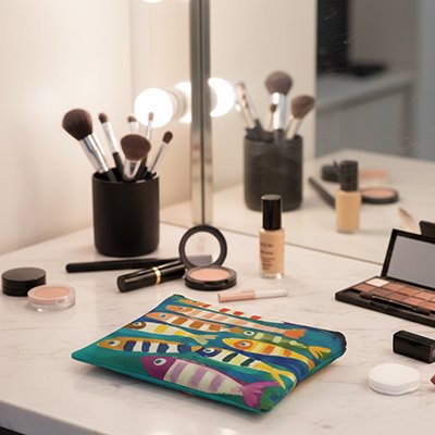 Trousse à maquillage colorée à motifs poissons, posée sur coiffeuse