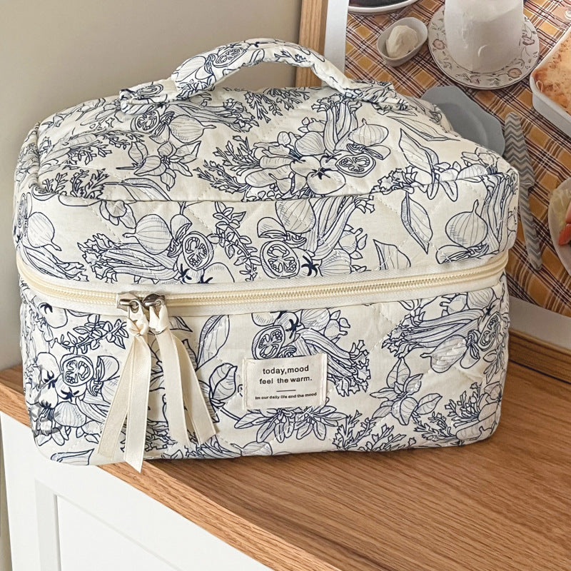 trousse de maquillage matelassée élégante fleurie avec grande capacité sur table de bois