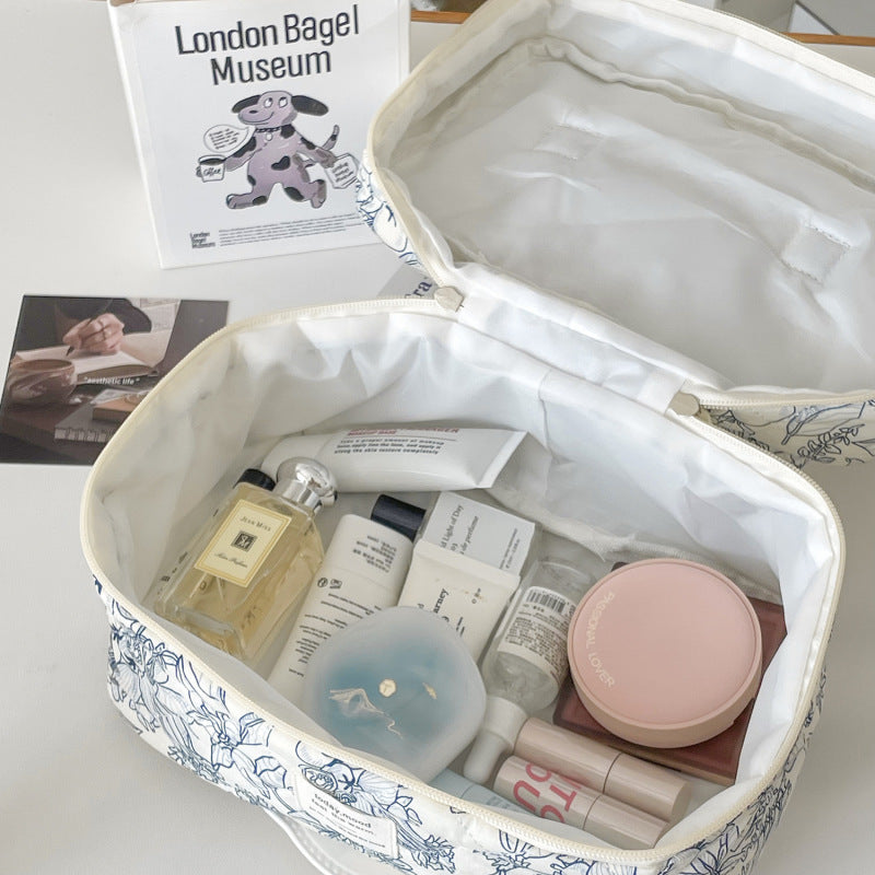 trousse de maquillage ouverte matelassée élégante fleurie avec grande capacité sur bureau blanc