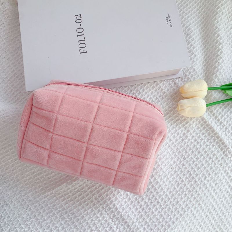 trousse à maquillage velours matelassé rose posée sur table blanche style minimaliste