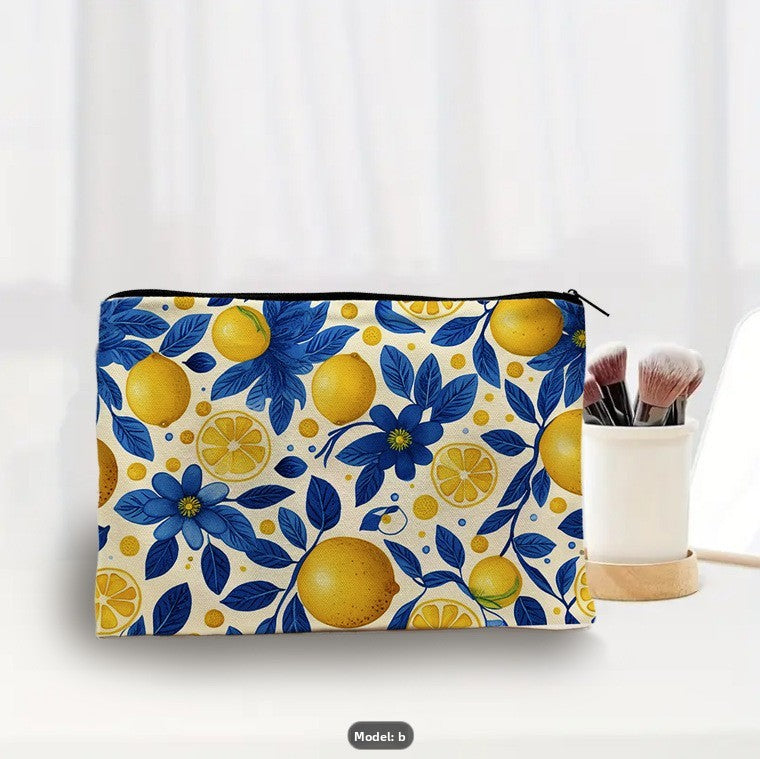 trousse de maquillage fantaisie motif citrons jaunes et fleurs bleues posée sur table blanche avec gobelet de pinceaux