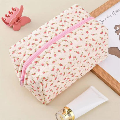 Trousse de maquillage rose en coton matelassé, fermée, exposant son élégance et son design fleuri.