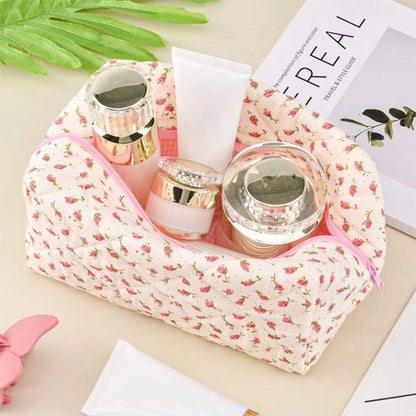 Trousse de maquillage rose en coton matelassé, ouverte, exposant divers flacons de produits, démontrant sa grande capacité.
