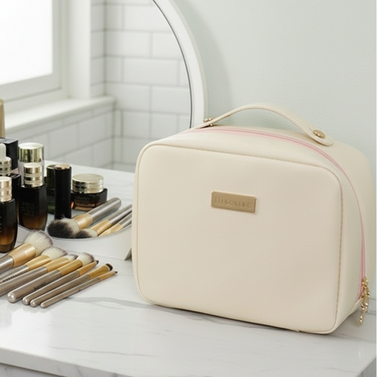 Trousse de toilette femme beige crème , posée sur une coiffeuse, maquillage et pinceaux disposés sur un comptoir style marbre élégant.