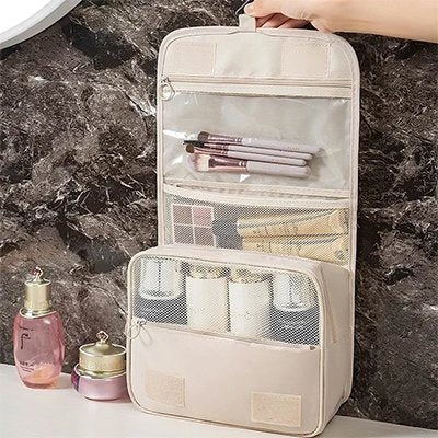 trousse de toilette voyage beige ouverte pour exposer trois compartiments
