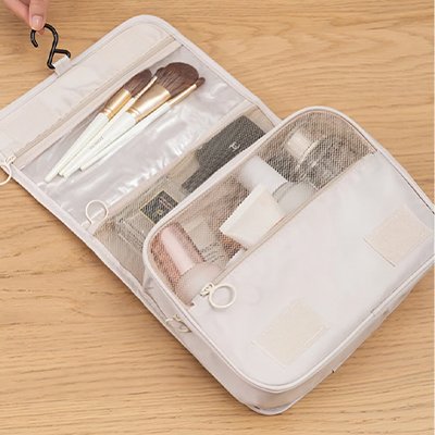 Trousse de toilette voyage beige sur table en bois démontant les divers compartiments