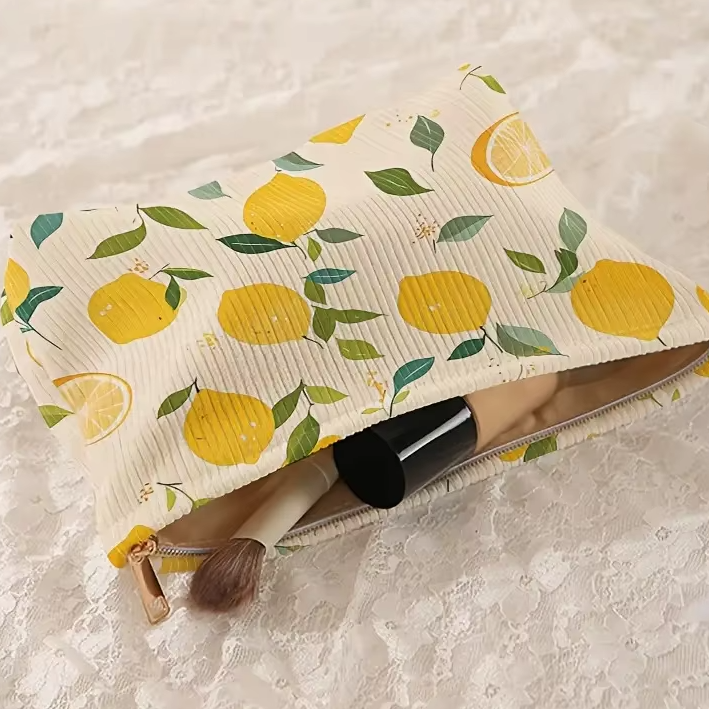 trousse maquillage à citrons posée sur dentelle, avec pinceau et produit cylindrique