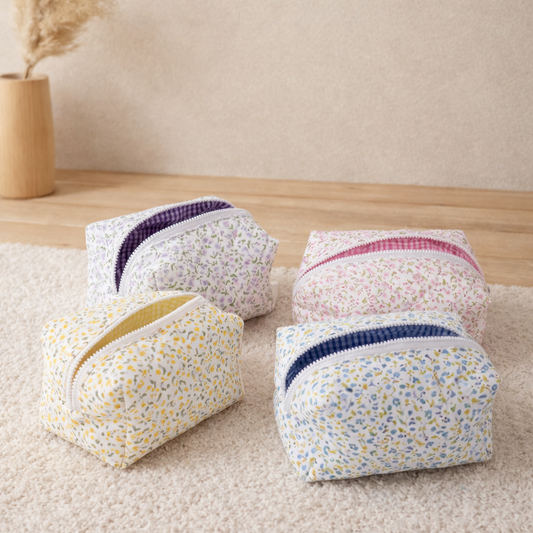 trousse maquillage fleurie matelassée posée au sol décor zen bois clair mur beige lumière douce quatre modèles