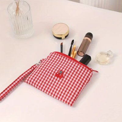 Trousse maquillage rouge à carreaux souple posée sur coiffeuse 